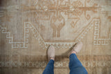 Close-up of distressed Oushak rug, highlighting geometric motifs in sand and coffee brown.
