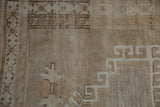 Distressed Oushak short pile with faded beige and brown hook and latch motifs.