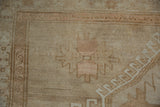 Distressed vintage Oushak rug corner with short pile, sand, beige, and soft apricot motifs.