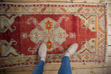 Distressed cherry red abrashed field with serrated platinum and pale tangerine geometric patterns.