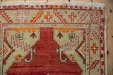 Oushak rug detail with cherry red, saffron, and platinum geometric floral motifs and fringe.