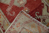 Distressed cherry red pile, fringed edge, and hand-knotted geometric reverse of the Oushak runner.