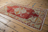 Distressed Oushak runner corner; cherry red field, platinum border with geometric florals, worn fringe.