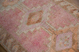 Distressed vintage Kurd runner's textured pile showing worn pink, sand, and orange stepped pattern.