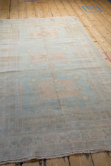 Angled view of a vintage Oushak runner showing beautiful abrashes across its sun-faded pastel pile.