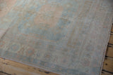 Low pile texture and sun-faded pastel hues on a vintage distressed Oushak rug corner.