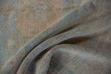 The weave of the distressed Oushak shows deeper tones beneath the sun-faded surface.