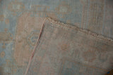 Folded corner of the vintage Oushak rug, showing its hand-knotted back and original side cord.