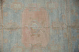 Varying pile height and sun-faded pastel blues and rose on a vintage Oushak rug.