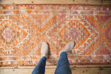 Distressed Kurd runner texture, revealing geometric patterns in tangerine orange and dusty magenta.