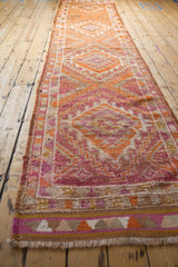 Angled view of the vintage distressed Kurd runner rug, highlighting worn geometric patterns in magenta and orange tones.