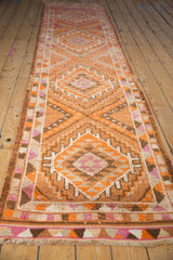 Distressed vintage Kurd runner, angled view showing geometric tangerine and magenta medallions.