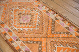 Distressed vintage Kurd runner displaying textured geometric patterns in tangerine, brown, ivory.