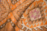 Vintage distressed Kurd runner pile showing wear, tangerine orange, ivory, and brown geometric pattern.