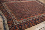 Corner of a Persian Afshar rug showing the plain weave kilim, fringe, and storied repair efforts.