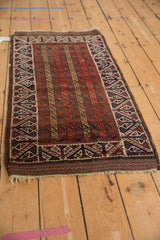 A wide, geometric border framing the parallel running channels of an antique Persian Belouch rug.