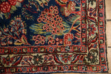 Vintage Qazvin rug corner: indigo field, meandering vine border, and intact selvage.