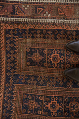 Close-up on the worn texture and pawn design motifs of a vintage Belouch rug.