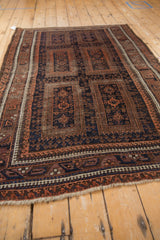 Angled perspective of the vintage Belouch rug's multi-panel design in navy, terracotta, and brown.