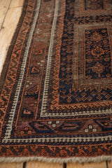 A vintage Persian rug's reciprocating pawn motif border with wear visible to the knot heads.