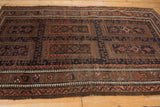 Low-angle view showing the multi-panel design and pawn motif border of a vintage Belouch rug.