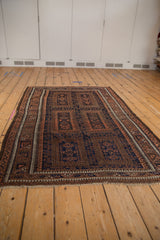 A full, angled view of a vintage Persian Belouch rug showing its repeating geometric panels.