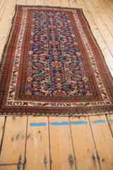 Vintage Malayer rug corner with indigo blue field, intricate floral motifs, and rich burgundy borders.