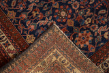 Folded corner of a Vintage Malayer rug revealing rich indigo floral motifs and hand-knotted foundation.