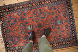 Navy floral border and brick red field featuring germinating plant motifs on vintage Lilihan rug.