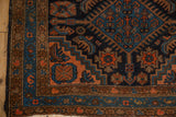 Herati field and boteh border of a Vintage Mehriban rug, in navy, madder red, and cantaloupe.