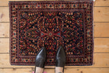 Vintage Sarouk rug corner: dark blue ground, raspberry red, antique ivory floral border.