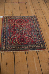 Angled view of a vintage Sarouk square mat, showing its full floral design in red and blue.