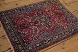 High-angle view of a vintage Sarouk rug, highlighting its cherry red floral sprays and navy border.