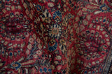Detailed texture of the hand-knotted pile on a vintage Sarouk rug with red and blue floral motifs.