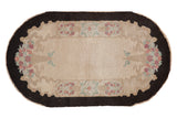 Vintage Fette-Li rug with a scalloped beige field, dark border, and mirrored floral bouquets.