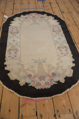 Vintage Fette-Li rug from an angle, showcasing floral baskets and a charcoal cloud-band border.