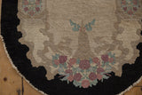 Detail of a vintage Fette-Li rug's charcoal cloud band border and dusty rose floral blossoms.
