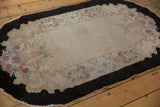 The unique scalloped charcoal border and floral corner detail of a vintage hand-knotted Fette-Li rug.