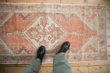 Vintage Distressed Oushak rug section with worn pale orange and green geometric patterns.