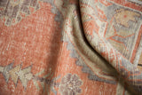 Worn texture and muted pattern details in pale orange, aubergine, and seafoam green.