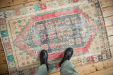 Distressed vintage Oushak rug center featuring dusty royal blue medallion and pac-man stylized blossoms.