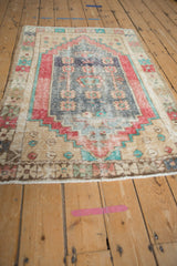 Distressed Oushak rug corner showing pac-man floral blossoms, dusty royal blue, and pale cherry red.