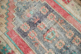 Distressed Oushak rug featuring faded dusty blue, red, and turquoise pac-man blossoms.