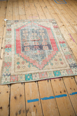 Lower corner detail of distressed Oushak rug, with stepped design in rose, sand, and turquoise.
