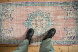 Distressed Oushak rug: dusty rose field, faded turquoise scalloped medallion, visible wear.