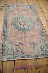 Distressed Oushak rug corner detail, faded turquoise spandrel, dusty rose field, meandering vine border.