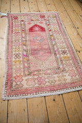 Distressed pink Oushak rug corner displays faded floral motifs and barber pole borders.