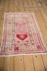 Distressed pile of a vintage Turkish Oushak rug with finned floral motifs and colorful barber pole borders.