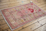 Distressed corner of a vintage Oushak rug, highlighting worn floral motifs and intact fringe.