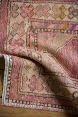 Distressed pink and ivory Oushak rug showing aged floral patterns and barber pole border.